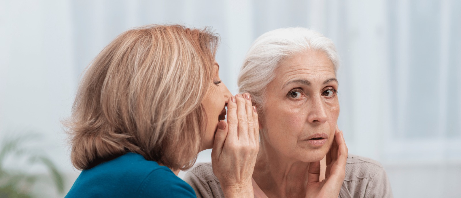Hearing Loss and Difficulty in Conversation – A Link to Depression A senior person looking isolated while others engage in a lively conversation, highlighting the impact of hearing loss on emotional well-being.